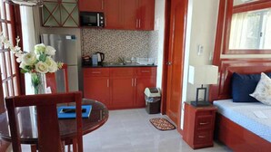 A compact room with a bed, a small desk, a dining table, and a kitchenette. - Ocean Breeze Resort (Toledo City)