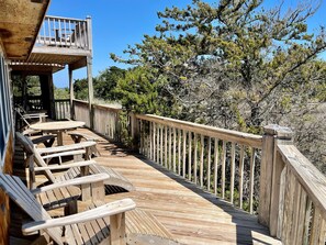 A wooden deck with outdoor seating and a railing, surrounded by trees.