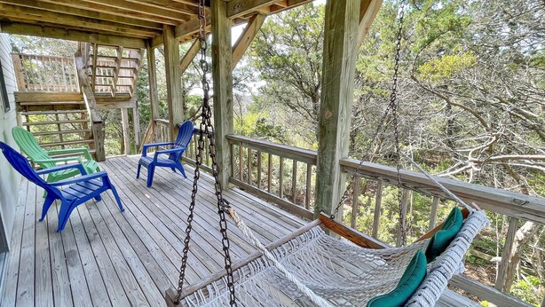 A wooden deck with a hammock and two chairs, surrounded by trees. - Wild Peony:  Incredible views from the ever popular rooftop deck! (Ocracoke)