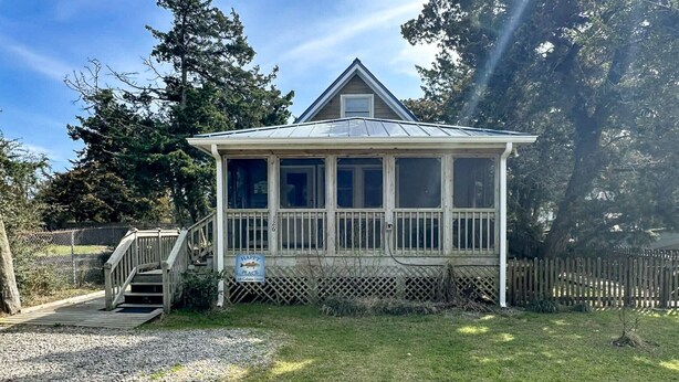 A small, single-story building with a covered porch, a staircase leading up to it, and a sign indicating it is a place to eat. - Happy Place:  Pet friendly, fenced rear yard with deck. (Ocracoke)