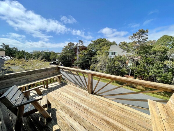 A wooden deck with a bench and a railing, overlooking a residential area with houses and trees. - Jack Stocks' Place: Bright and cheerful, centrally located. (Ocracoke)