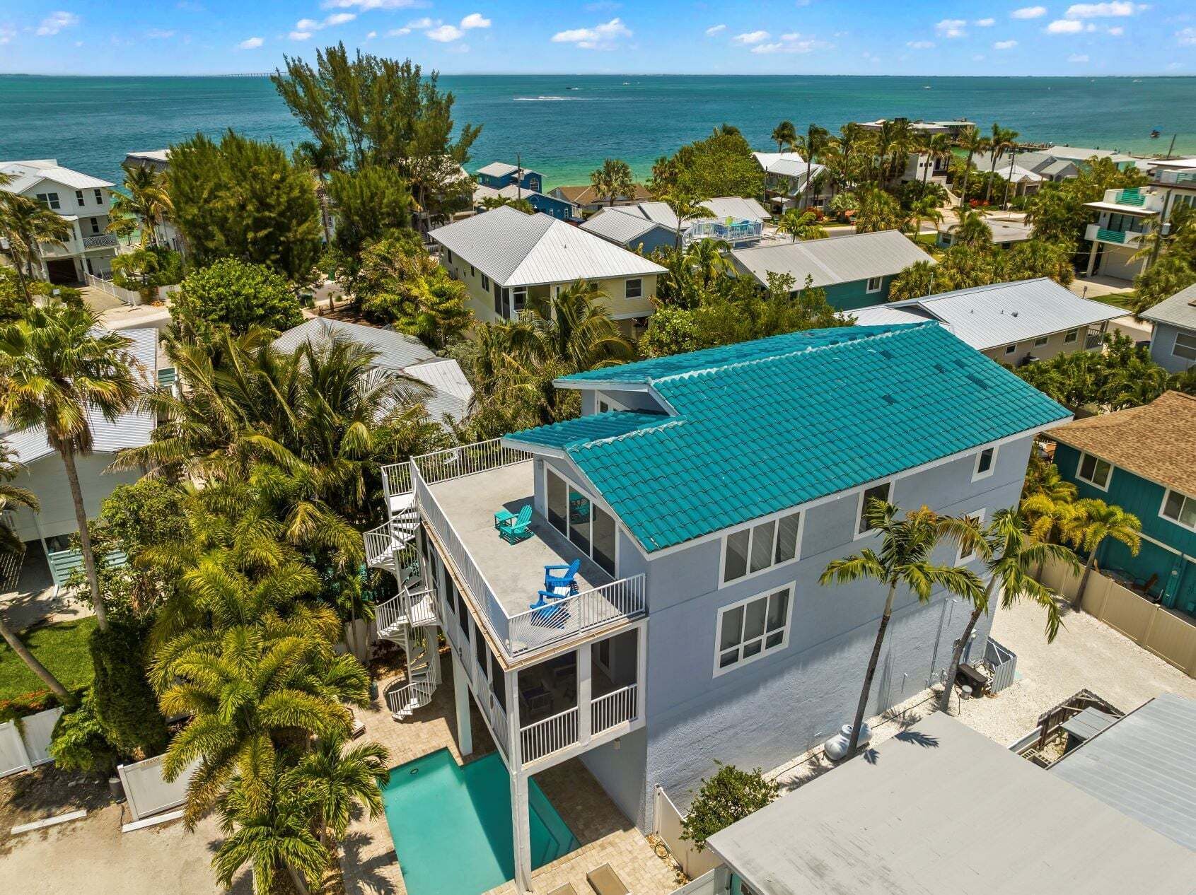 Un quartier résidentiel situé sur la côte, avec une maison dotée d’un balcon, d’une piscine et offrant une vue sur l’océan.