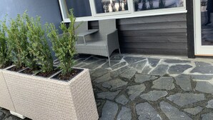 A patio area with a stone floor, wicker furniture, and potted plants. - Husnes Sentrum Hotell (Kvinnherad)
