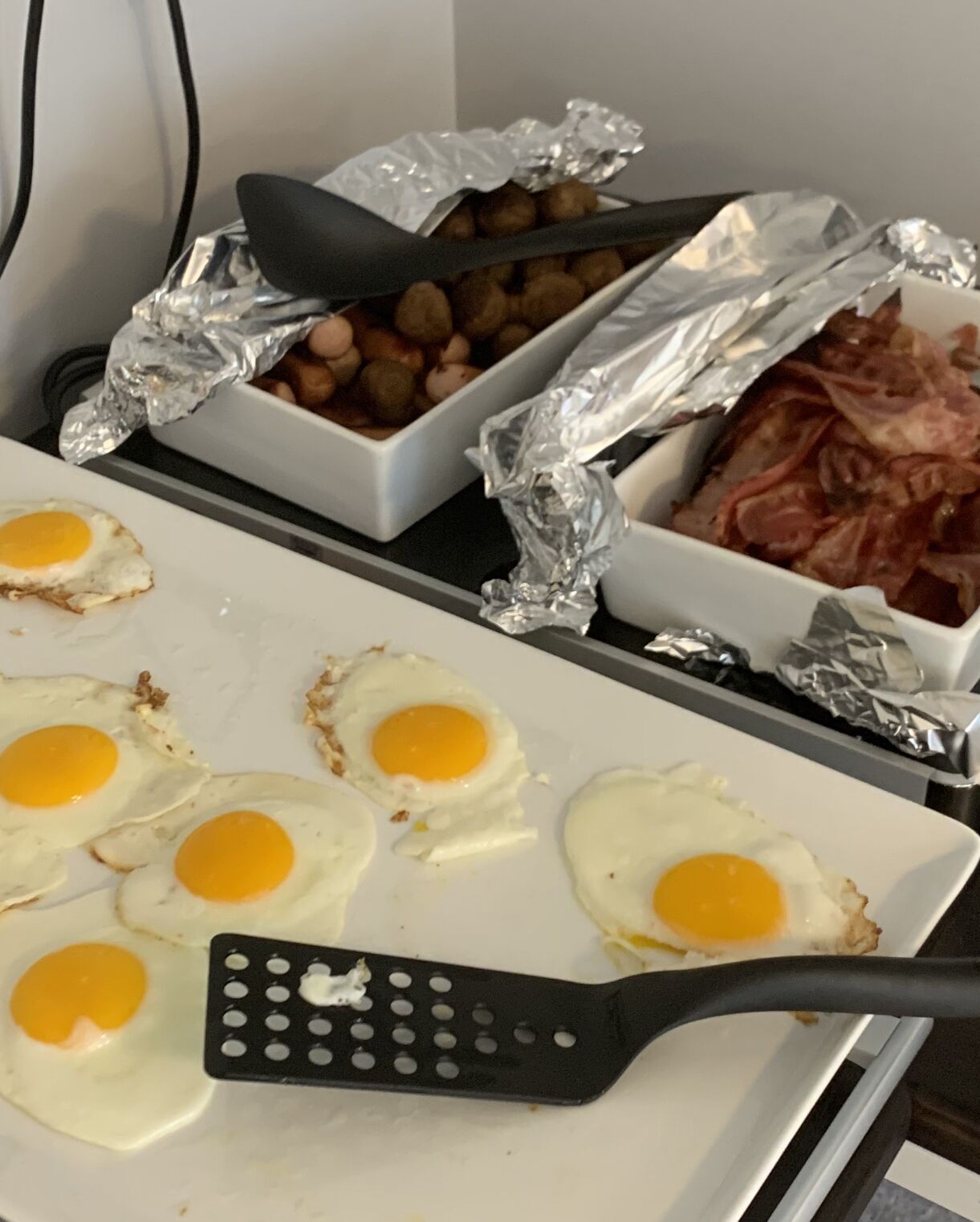 A breakfast tray with eggs, bacon, and beans.