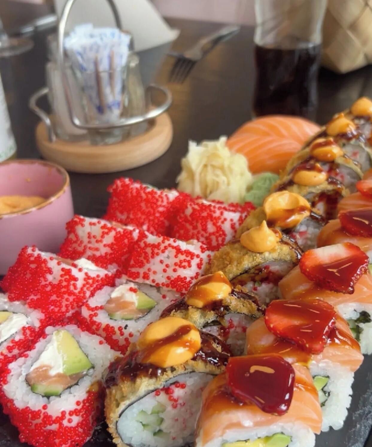 Variedad de rollos de sushi con diferentes ingredientes y salsas.