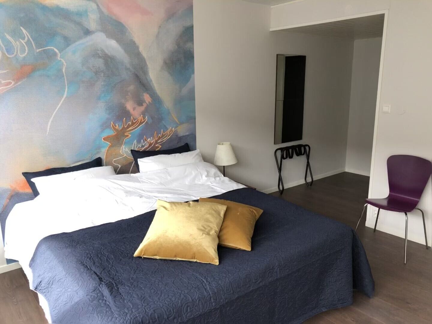 Habitación de hotel con una cama grande, una silla, un escritorio y un cuadro en la pared.