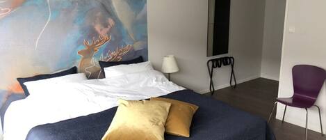 Habitación de hotel con una cama grande, una silla, un escritorio y un cuadro en la pared.
