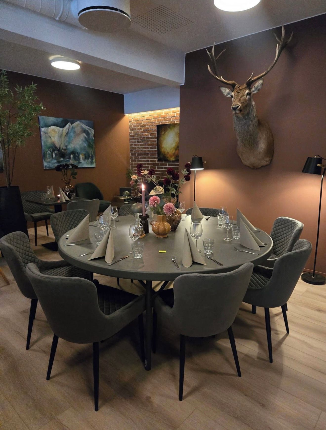A dining area with a round table set for six, surrounded by upholstered chairs.