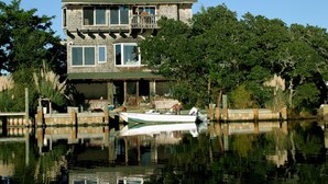 A two-story house with a dock and a boat. - Cuttin' Sage:  Tropical flavor, reverse floorplan, canal, marsh views. (Ocracoke)