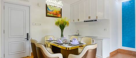 A modern kitchen with white cabinets, a dining table set for four, and a chandelier.