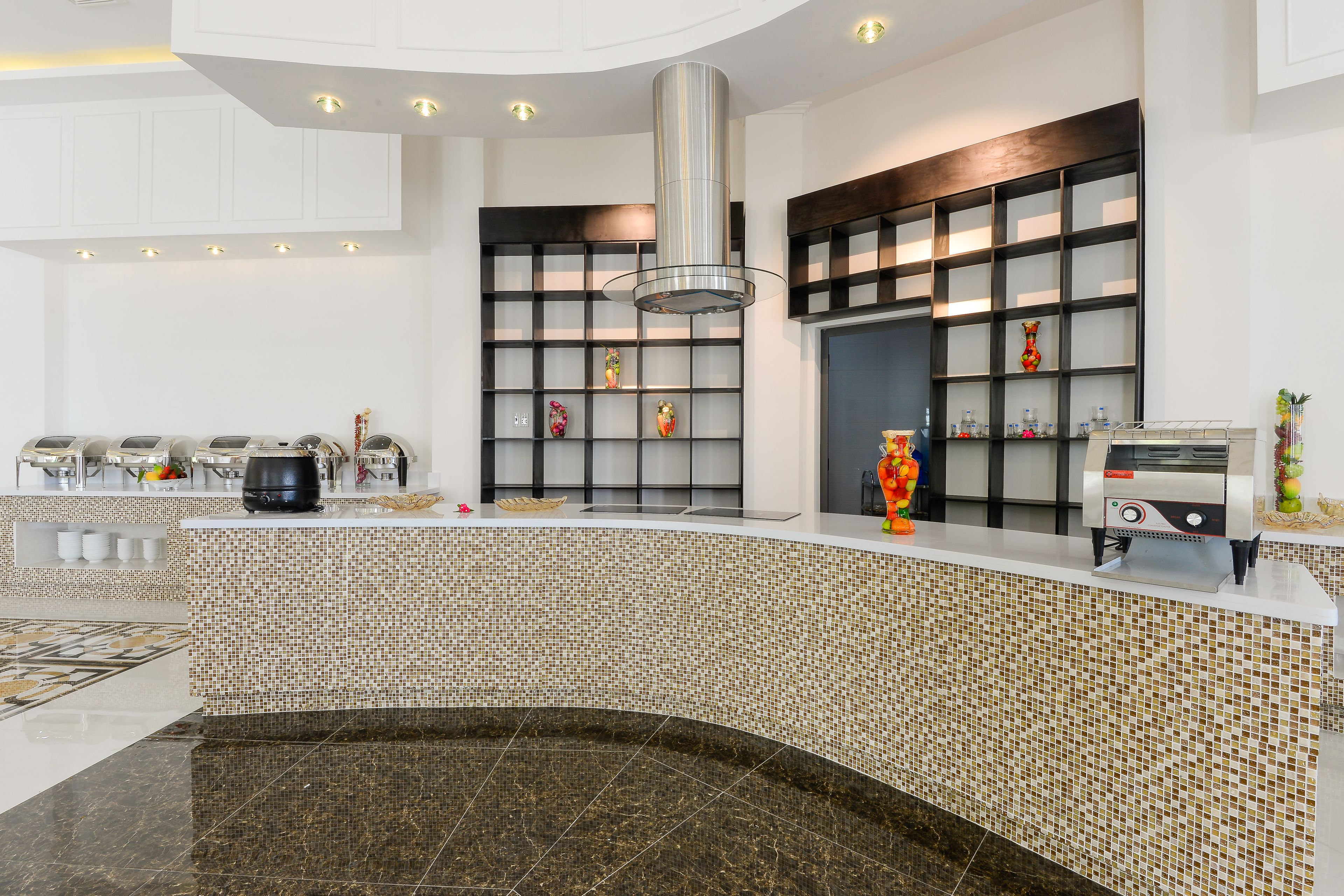 A modern kitchen with a tiled backsplash, a stainless steel range hood, and a coffee machine.