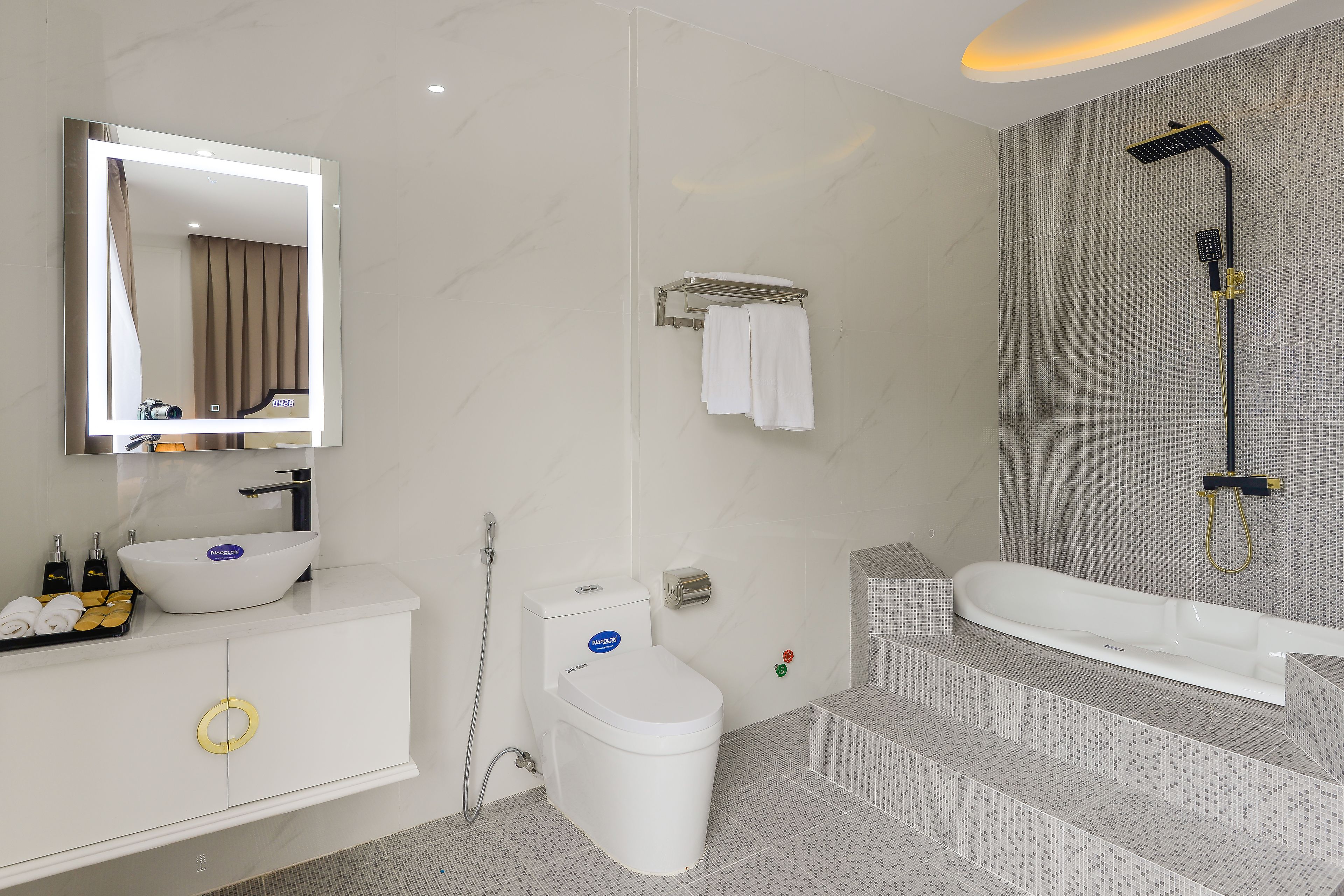A modern bathroom with a white vanity, a large mirror, a toilet, a shower, and a bathtub.