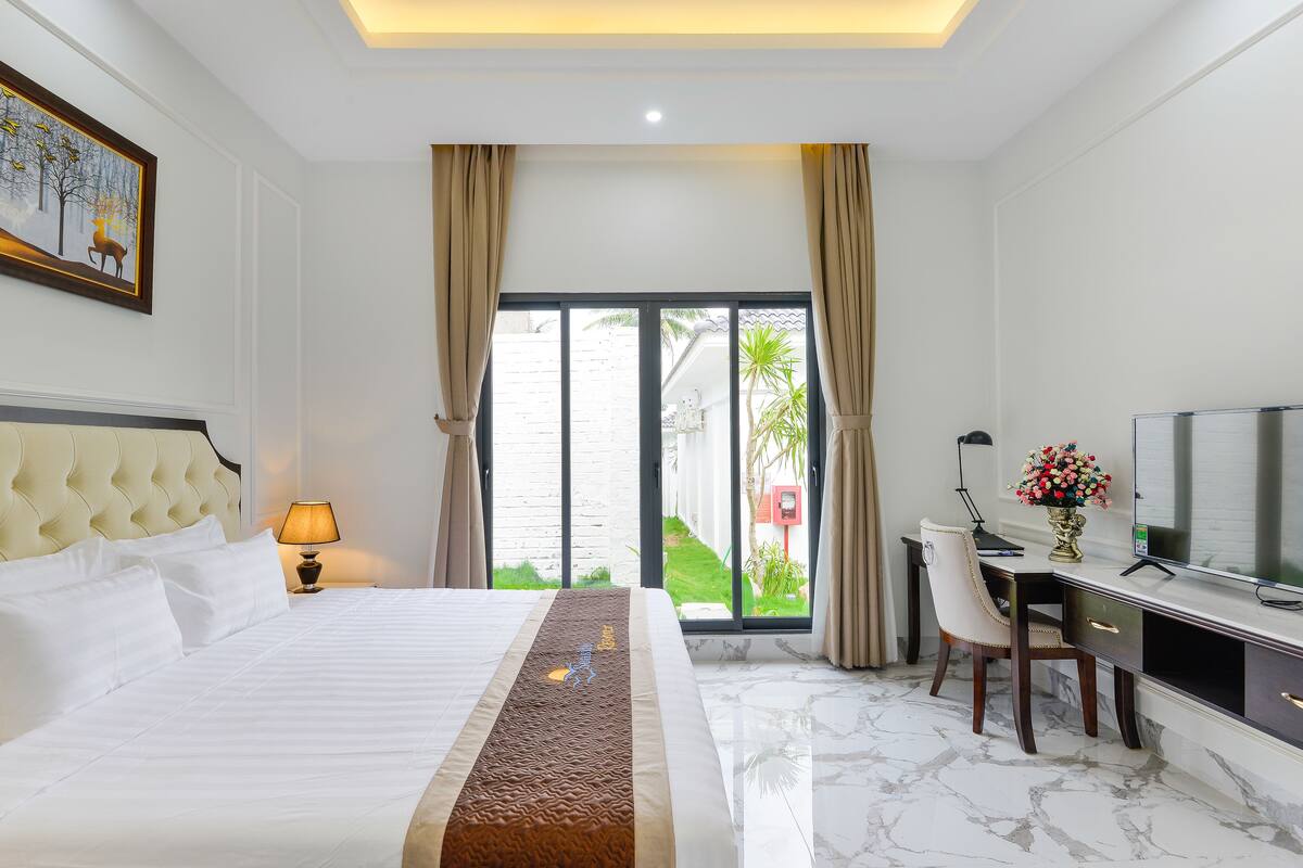Ein Hotelzimmer mit Bett, Schreibtisch, Fernseher und Blick ins Freie.
