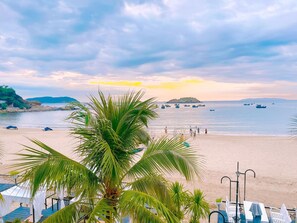 A beach with palm trees, a sandy shore, and boats in the water. - Seaside Boutique Resort Quy Nhon (Xuan Loc)
