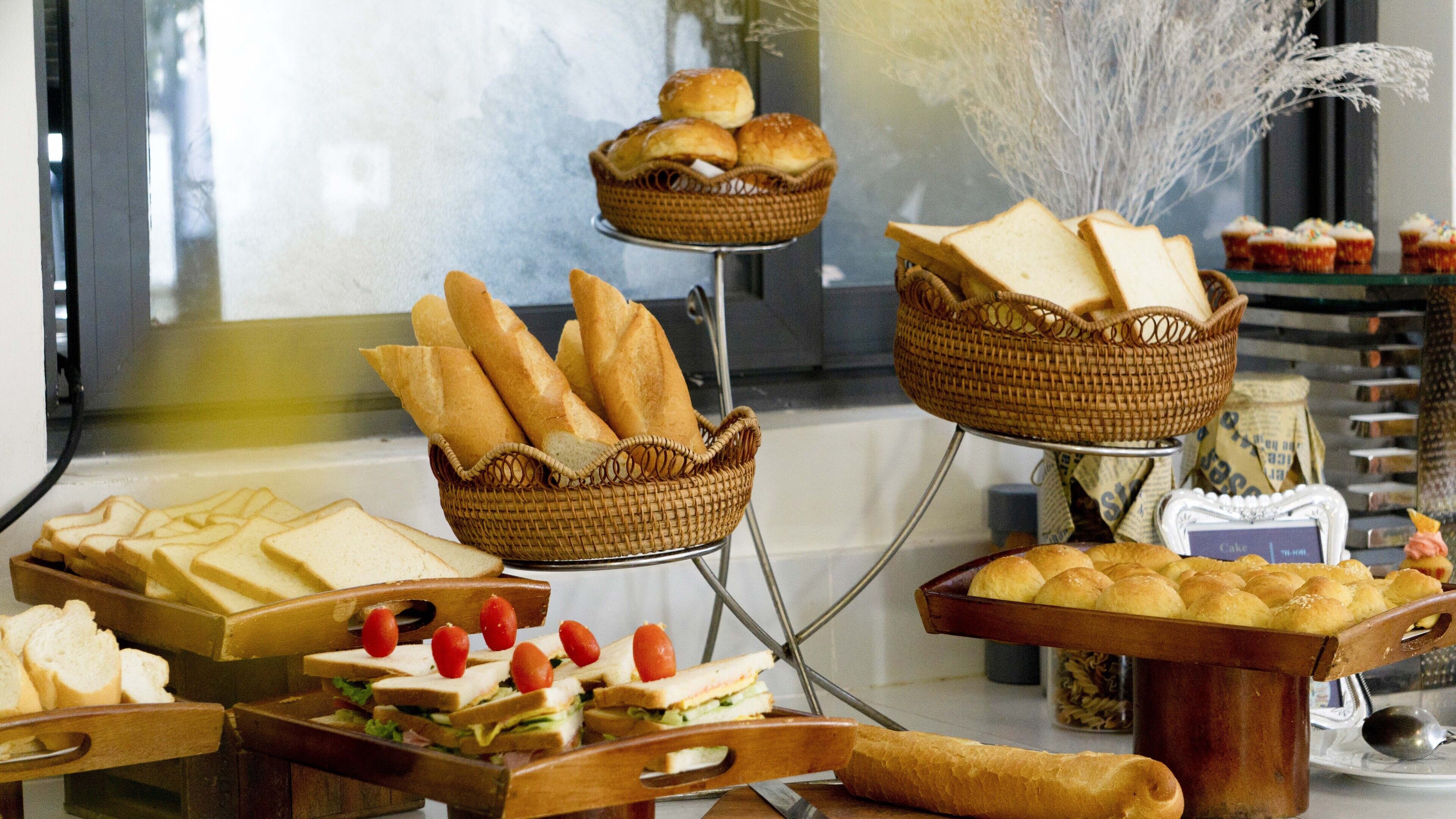 A buffet with various food items including bread, sandwiches, and pastries.