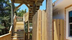 Une terrasse en bois avec un escalier menant à une zone abritée, le tout entouré d’une clôture en bois.