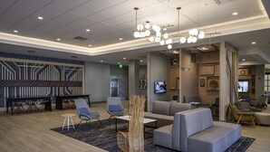 A modern lobby with seating areas, a piano, and a television. - Hyatt House Indianapolis / Fishers (Fishers)