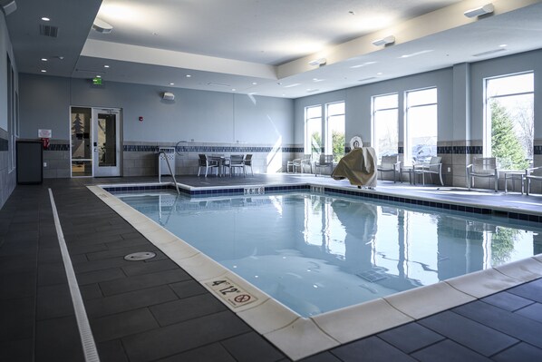 A swimming pool with a tiled deck, a covered seating area, and large windows providing natural light. - Hyatt House Indianapolis / Fishers (Fishers)