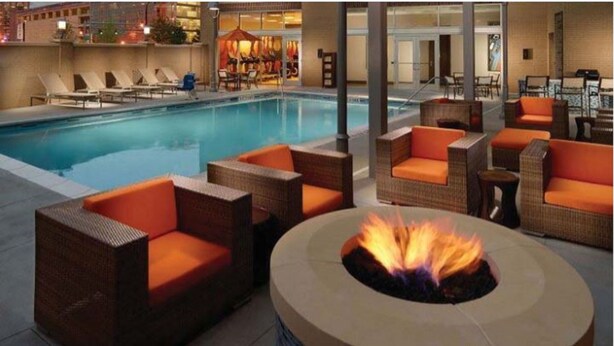 A poolside area with wicker furniture and a central fire pit. - Hyatt House Indianapolis / Fishers (Fishers)