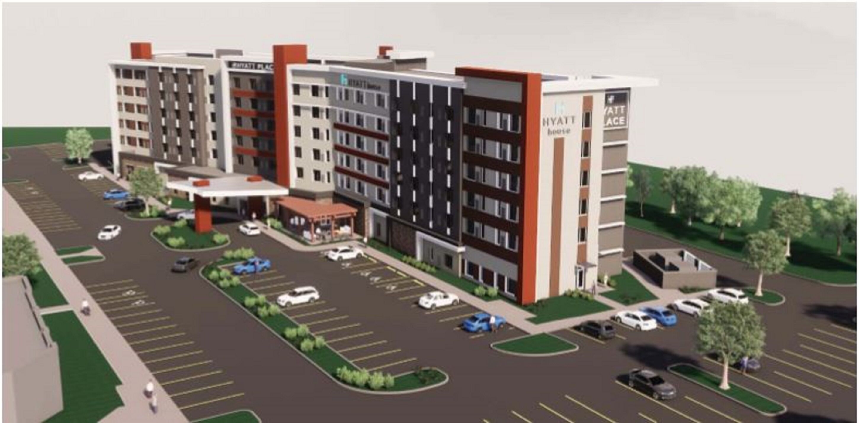 A multi-story hotel with a central courtyard, parking lot, and a visible entrance.