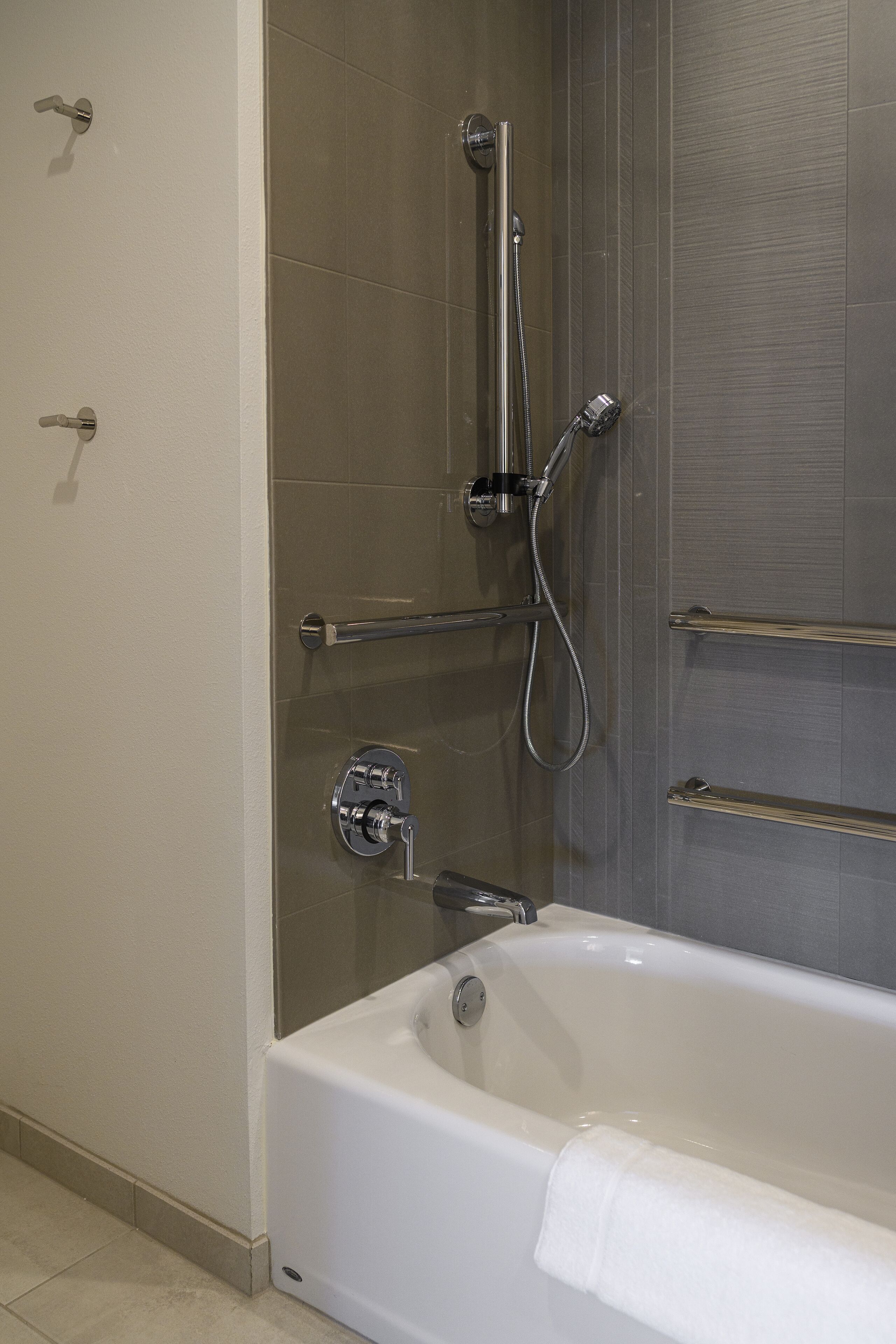 A modern bathroom with a glass-enclosed shower, a white bathtub, and a towel rack.