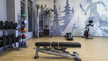 A gym with weightlifting equipment, exercise balls, and a wall mural.