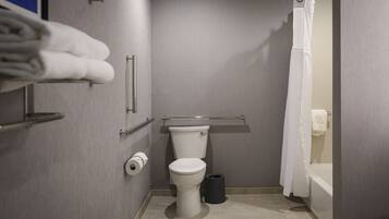 A compact bathroom with a toilet, a trash bin, a towel rack, and a shower curtain.