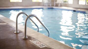 An indoor swimming pool with metal railings and a tiled edge.