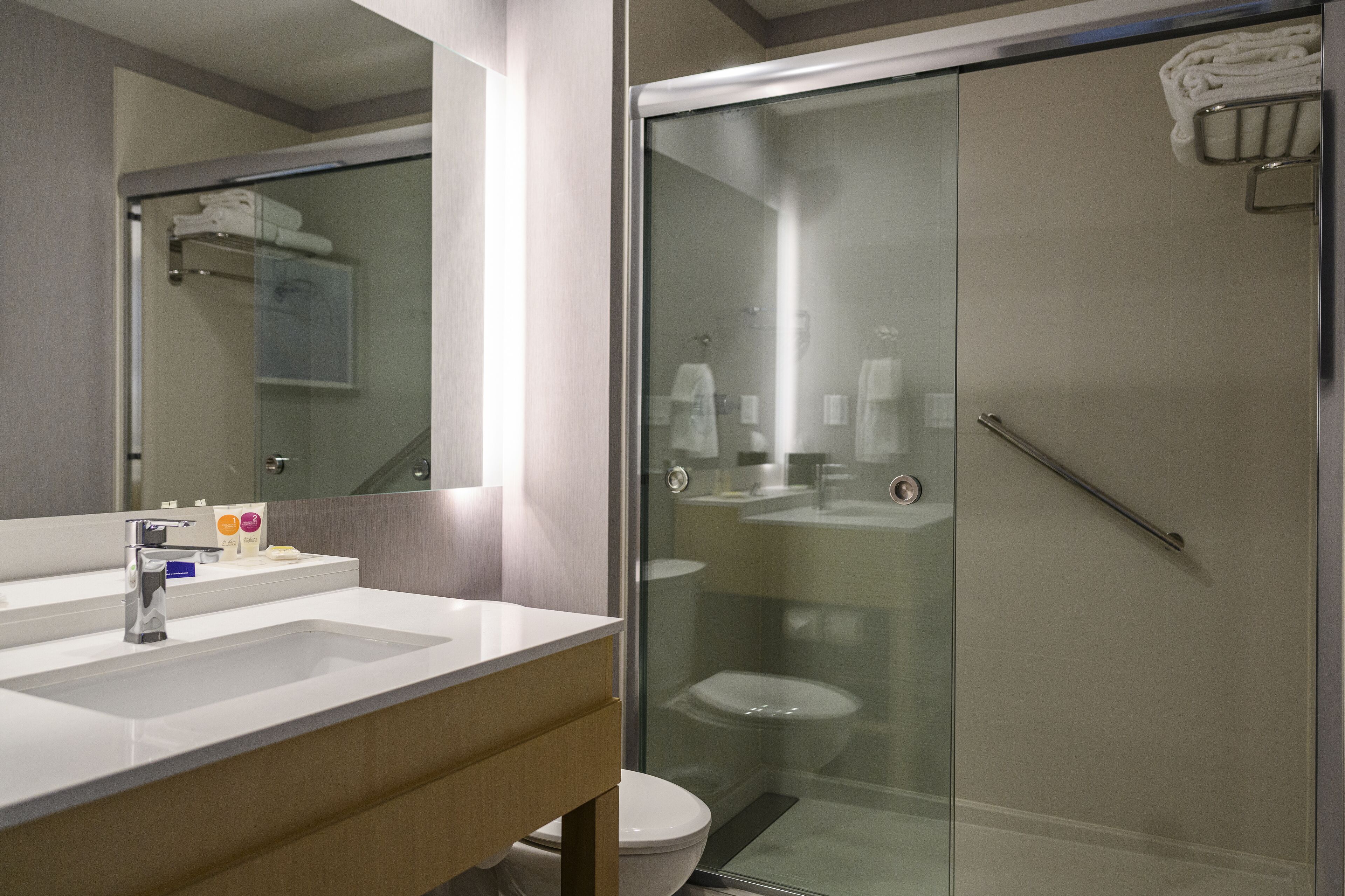 A modern bathroom with a glass-enclosed shower, a white sink, and a toilet.