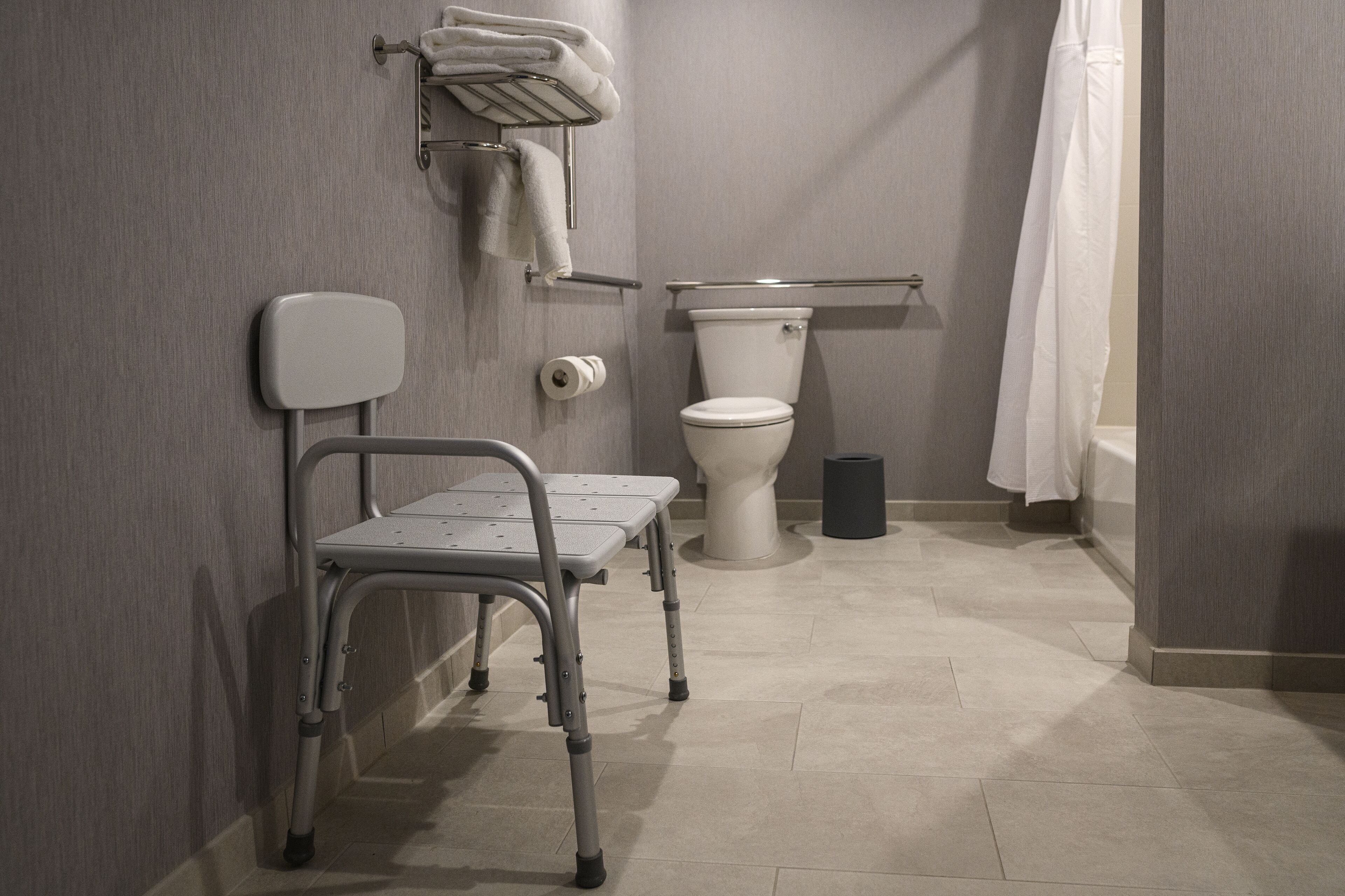 Et badeværelse med kørestol, toilet og bruseforhæng.