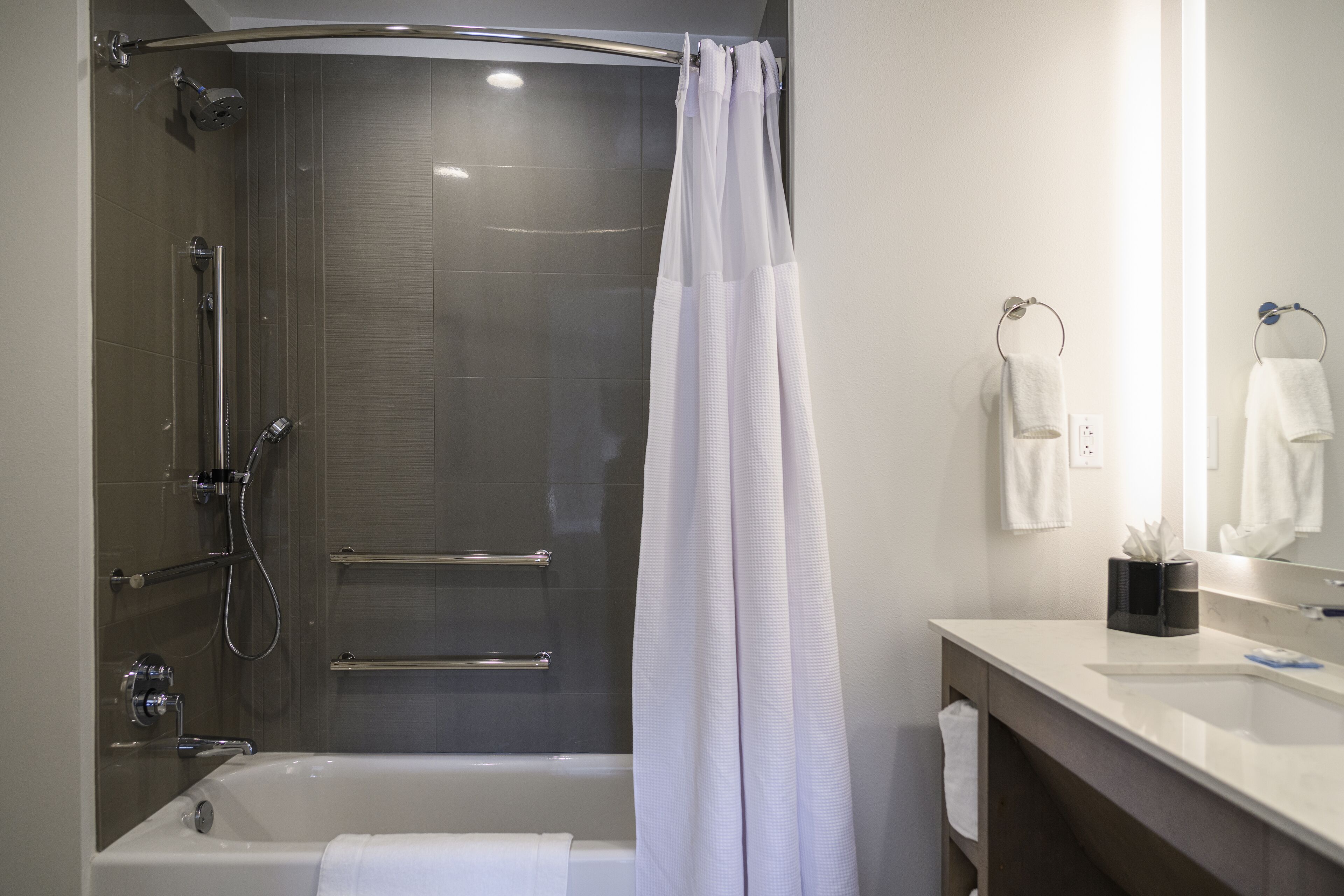 Un baño moderno con bañera, ducha y tocador con espejo.