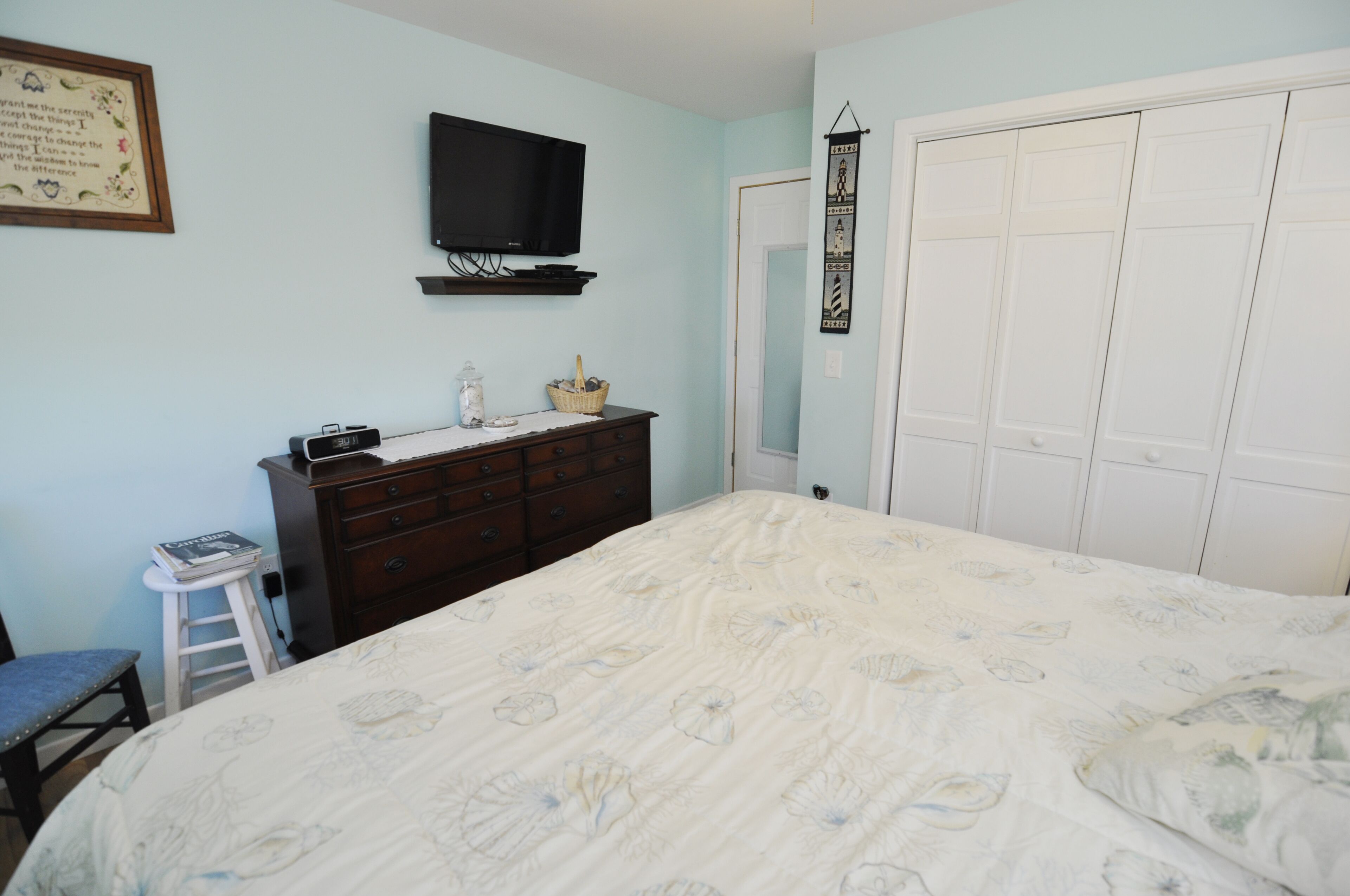 A bedroom with a bed, dresser, television, and a closet.