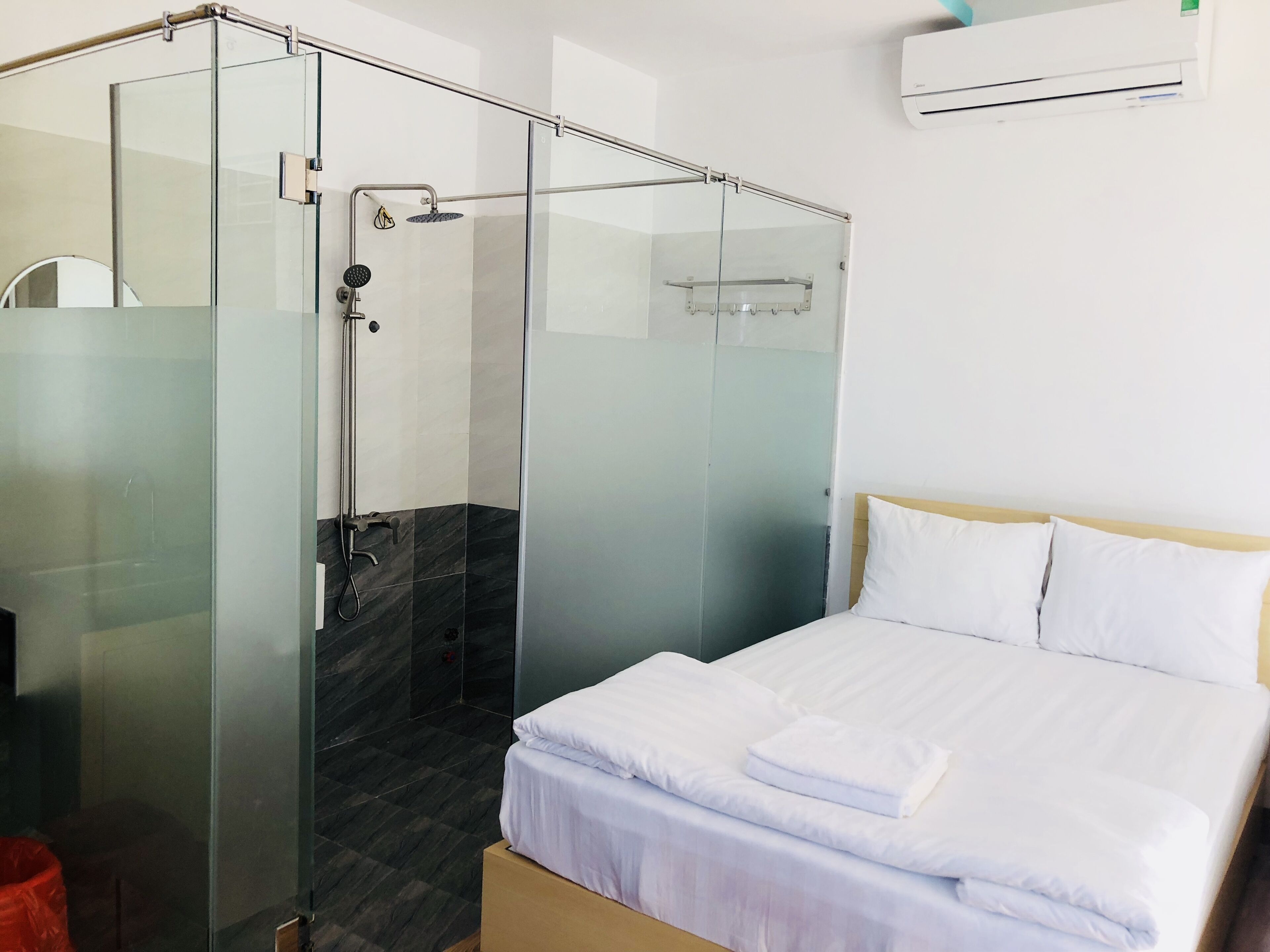 Una moderna camera d'hotel con cabina doccia in vetro, un letto con lenzuola bianche e un pavimento in marmo.