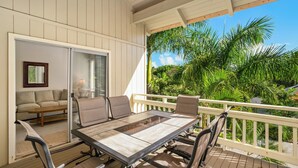 A covered outdoor dining area with a table and chairs, a sliding glass door leading to a living room, and a view of lush greenery. - South Shore Island Getaway at Poipu Crater 7 (Po'ipu)