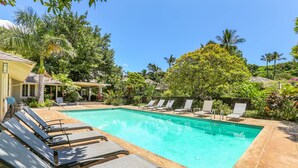 A rectangular swimming pool with clear blue water, surrounded by lounge chairs and palm trees. - South Shore Island Getaway at Poipu Crater 7 (Po'ipu)