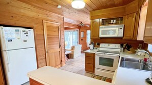 Una cocina compacta con gabinetes de madera, un refrigerador, un microondas, un horno y un lavamanos.