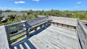 Una terraza de madera con vistas a un área boscosa y casas al fondo.