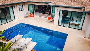 Ein modernes Haus mit Swimmingpool, großen Glasfenstern und einer Terrasse mit Sitzgelegenheiten.