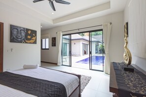 Ein geräumiges Schlafzimmer mit Bett, großem Fenster und Blick auf einen Swimmingpool.