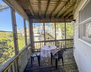 A covered porch with a table and chairs, overlooking a residential area with a staircase.