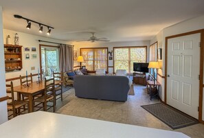 A living room with a sofa, TV, and dining area with chairs and a table.