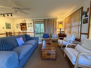 A living room with a sofa, armchairs, a coffee table, and a television.