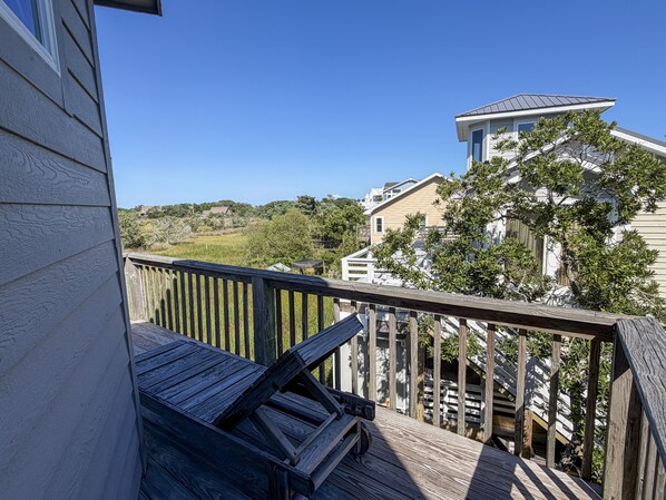A wooden deck with a view of a residential area, including houses and greenery.