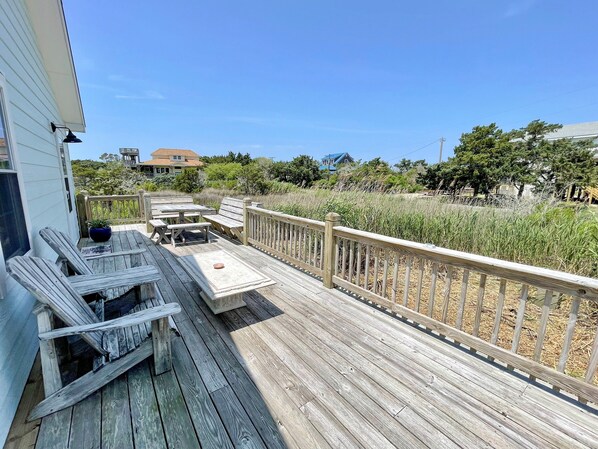 Une terrasse en bois, dotée de mobilier d’extérieur, d’une rambarde et offrant une vue sur le paysage environnant.