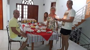 Un coin repas avec une table dressée pour quatre personnes, un escalier et une porte au fond.