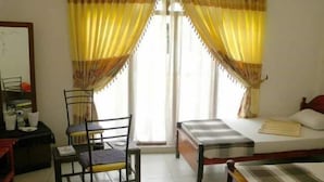 Une chambre à coucher avec un lit, un bureau avec une chaise et une fenêtre avec des rideaux.