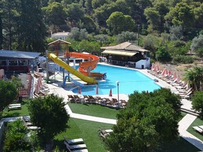 A swimming pool with slides, sun loungers, and a covered area. - Magda's Kamares (Poros)