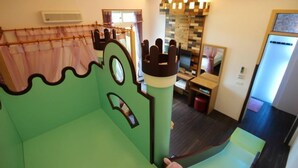 Zona de juegos infantiles con una cama con temática de castillo y una pequeña mesa con una silla.
