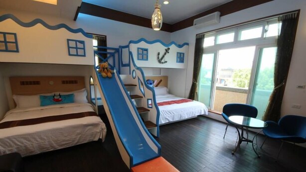 Habitación de hotel con literas, un tobogán, una mesita y sillas.