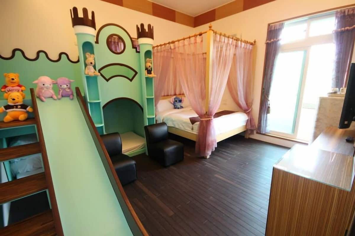 A children's bedroom with a bed, a play area with a slide, and a castle-themed wall.